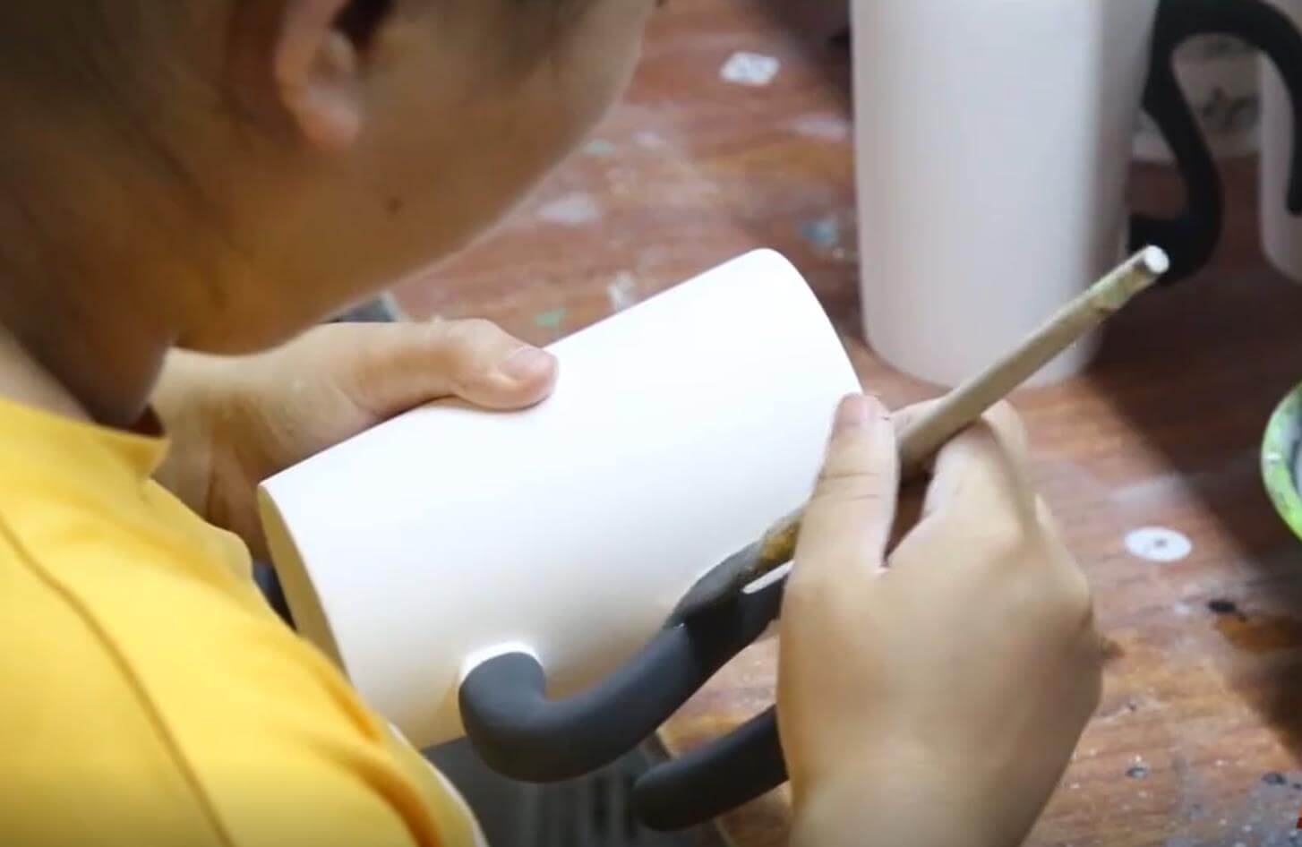 Craftsperson hand-painting ceramic details at the workbench in our Dehua factory